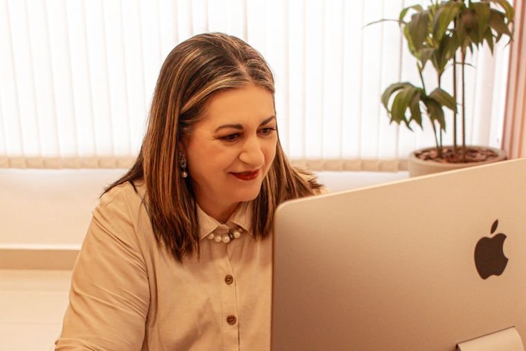 Luciane Melo atendendo por vídeo, no computador do consultório.
